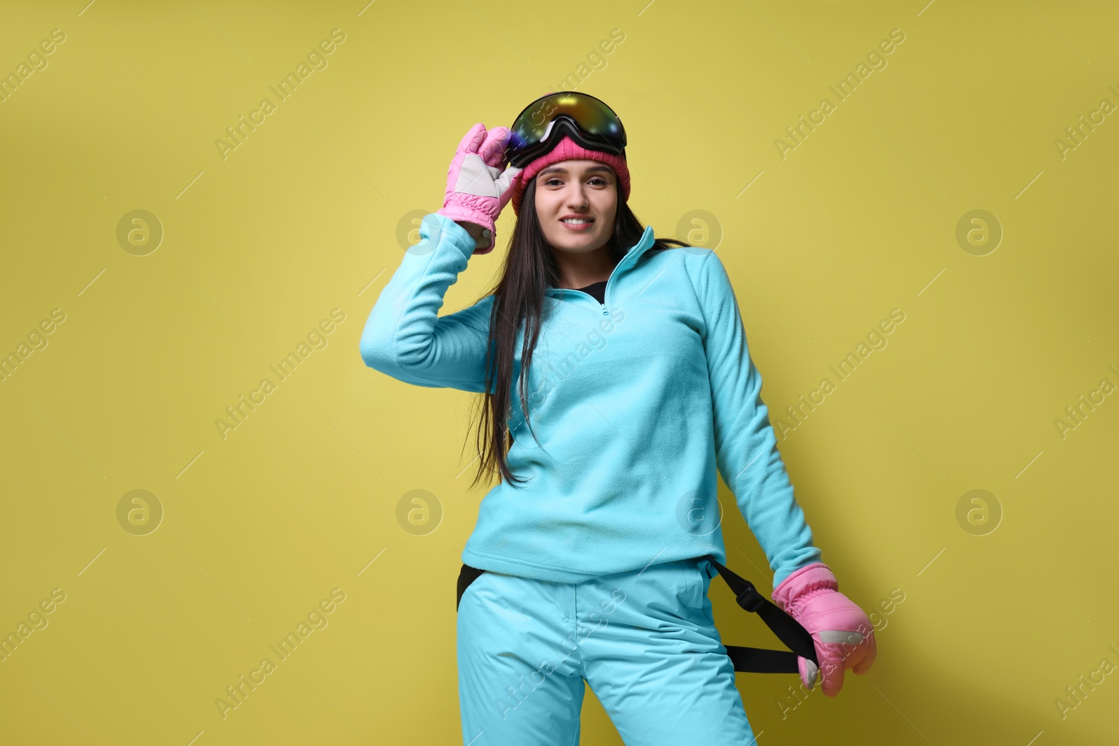 Photo of Woman wearing stylish winter sport clothes on yellow background, low angle view