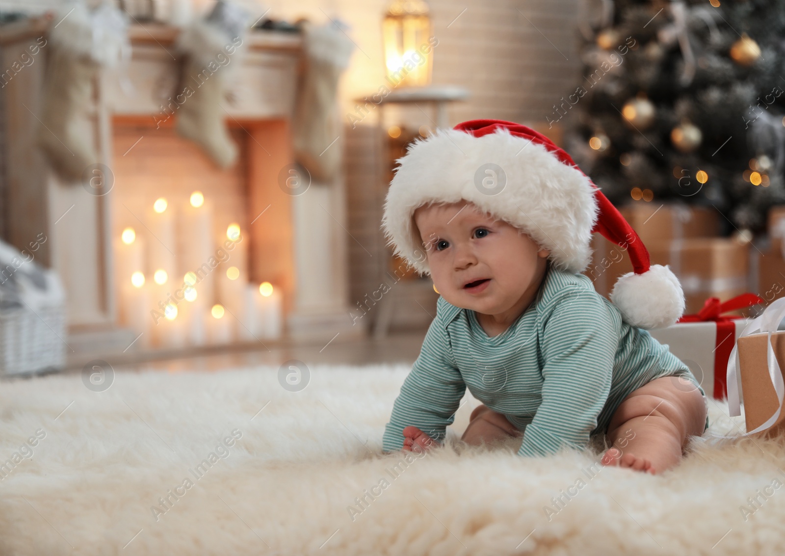 Image of Cute baby in Santa hat crawling on floor. First Christmas