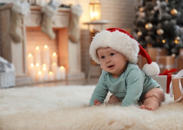 Cute baby in Santa hat crawling on floor. First Christmas