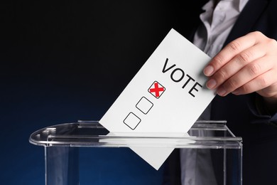 Image of Woman putting paper with word Vote and tick into ballot box on dark blue background