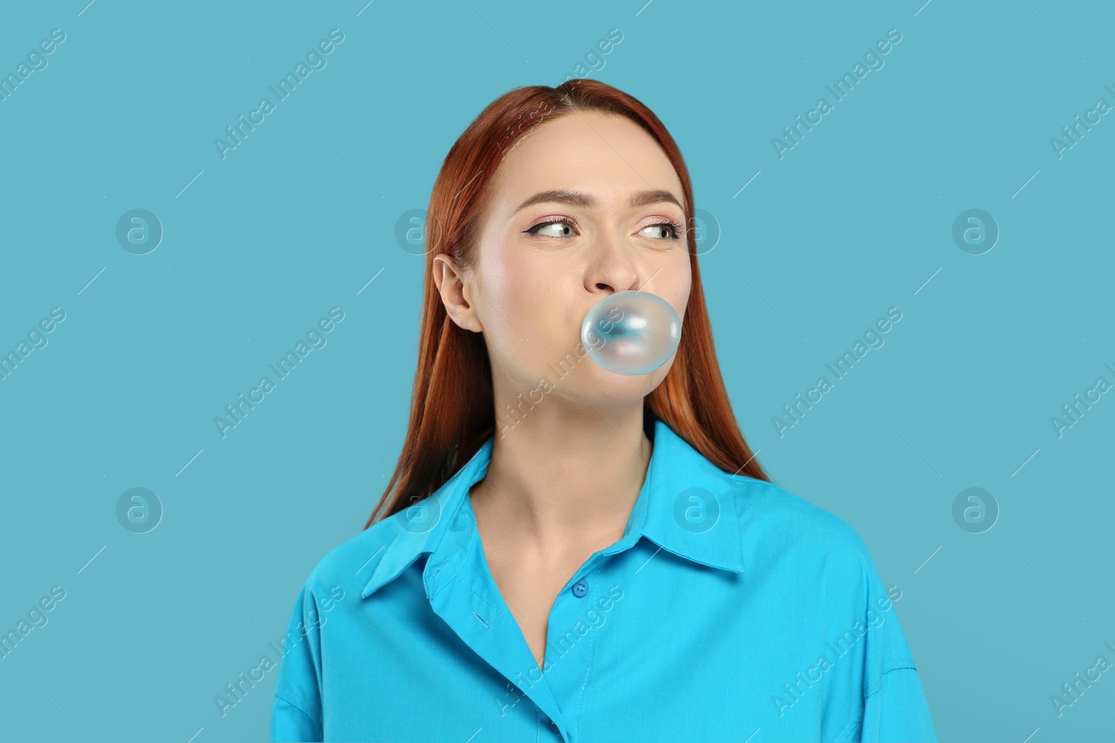 Photo of Beautiful woman blowing bubble gum on turquoise background