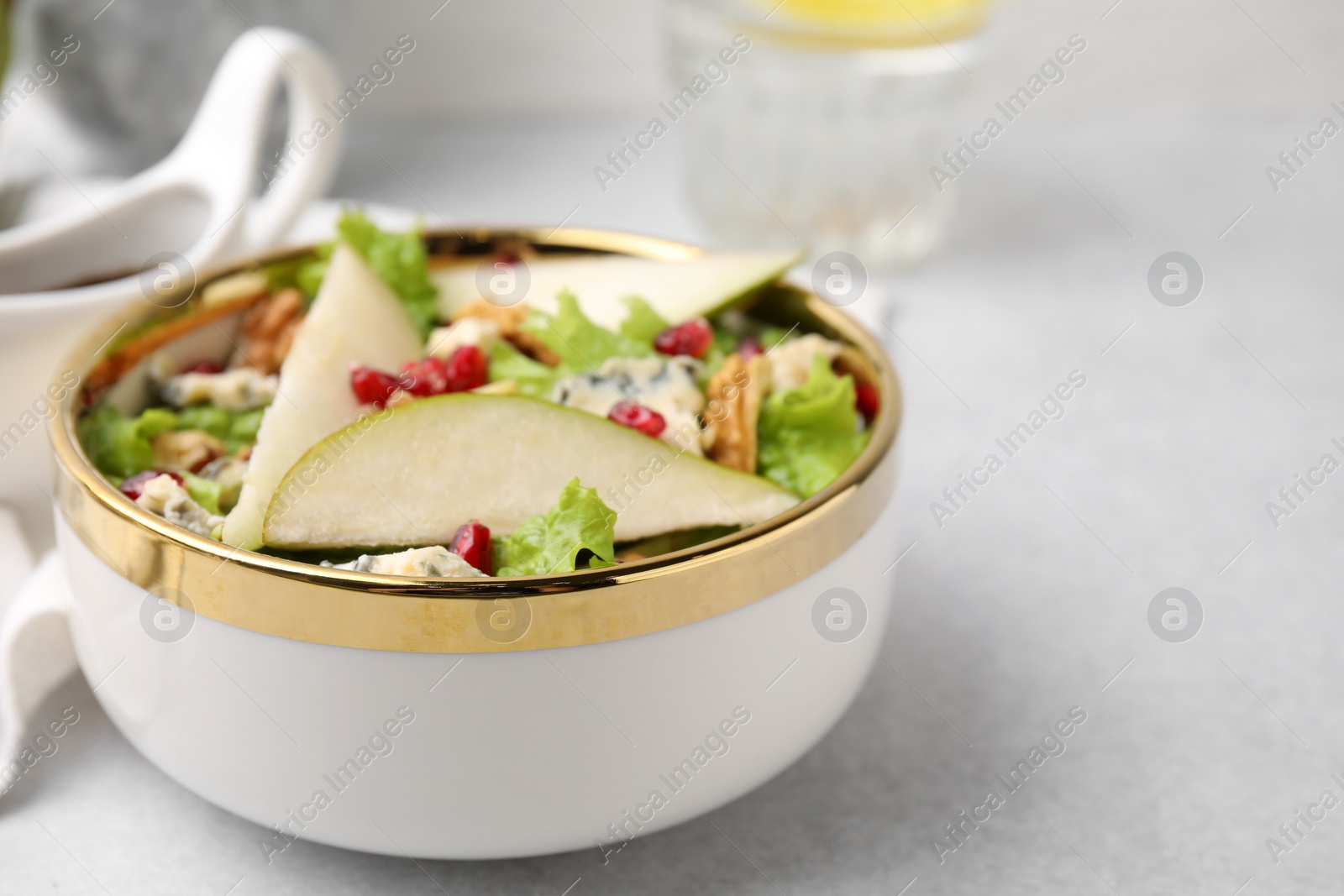 Photo of Delicious pear salad in bowl on light table, closeup. Space for text