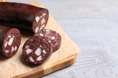 Photo of Tasty blood sausage on grey wooden table, closeup. Space for text