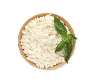 Delicious fresh cottage cheese with basil in bowl isolated on white, top view