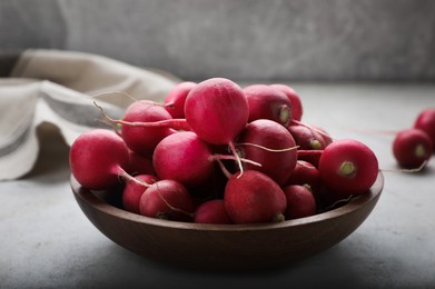 Photo of Wooden bowl with fresh ripe radishes on table, closeup