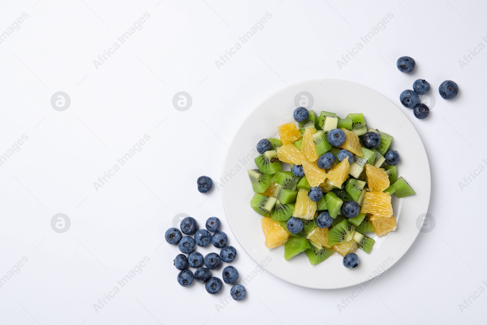 Photo of Plate of tasty fruit salad and blueberries on white background, flat lay. Space for text