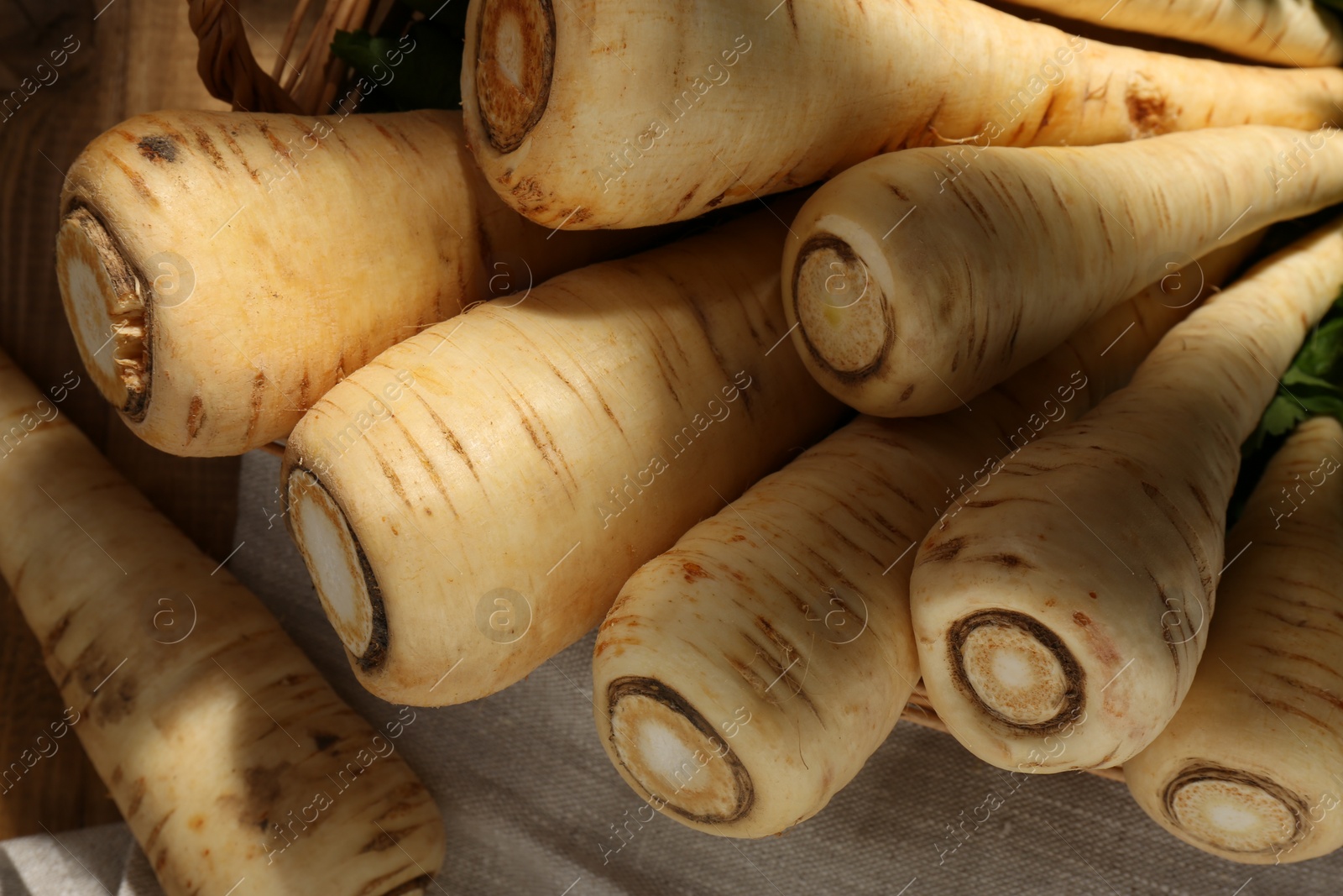 Photo of Wicker basket with delicious fresh ripe parsnips on wooden table, above view