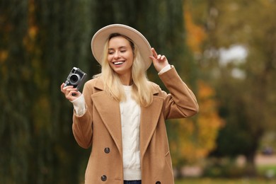 Photo of Portrait of happy woman with camera in autumn park