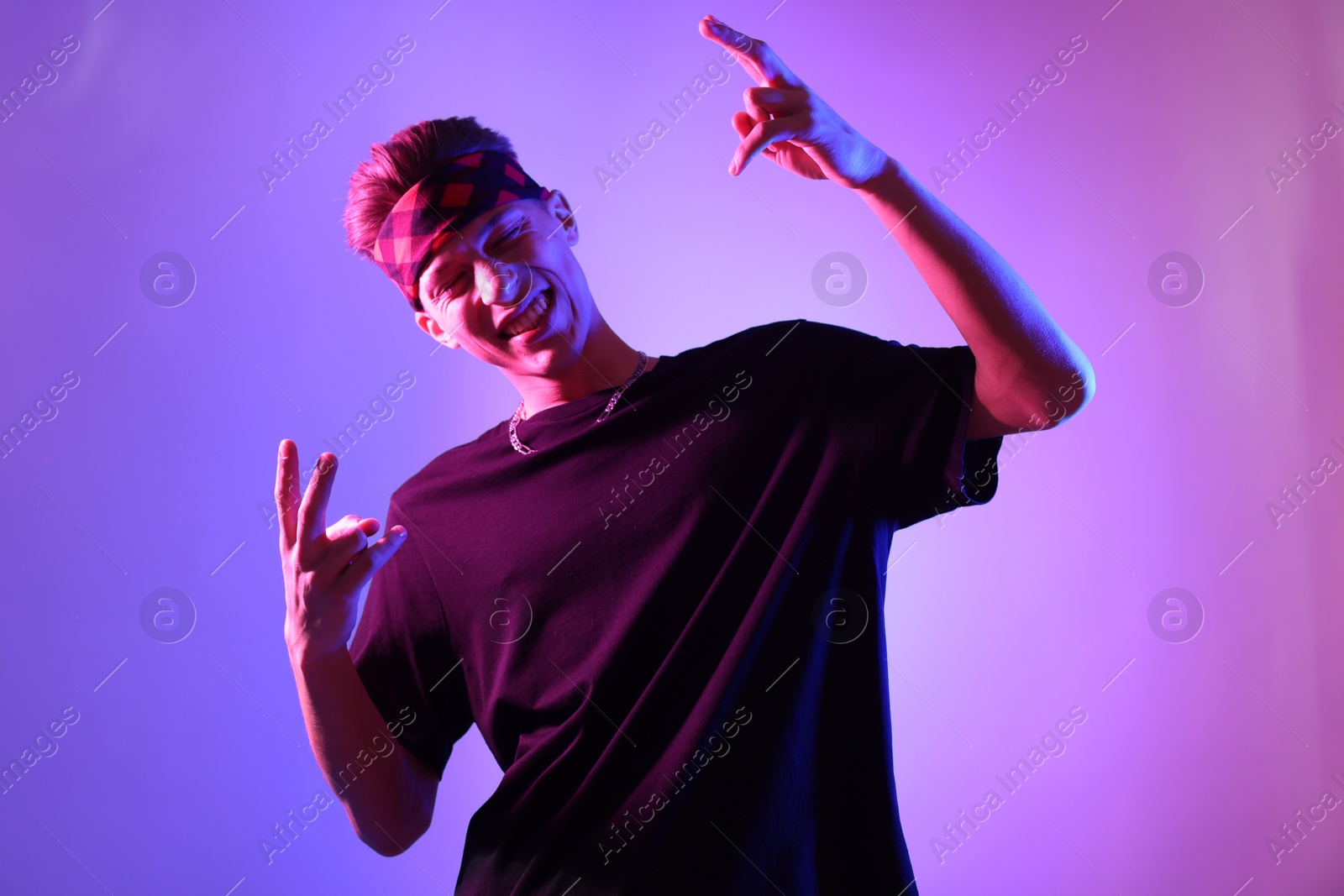 Photo of Stylish young man on color background in neon lights