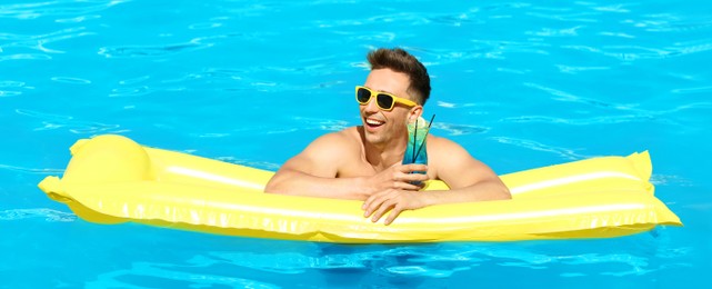 Happy young man with cocktail and inflatable mattress in swimming pool. Banner design