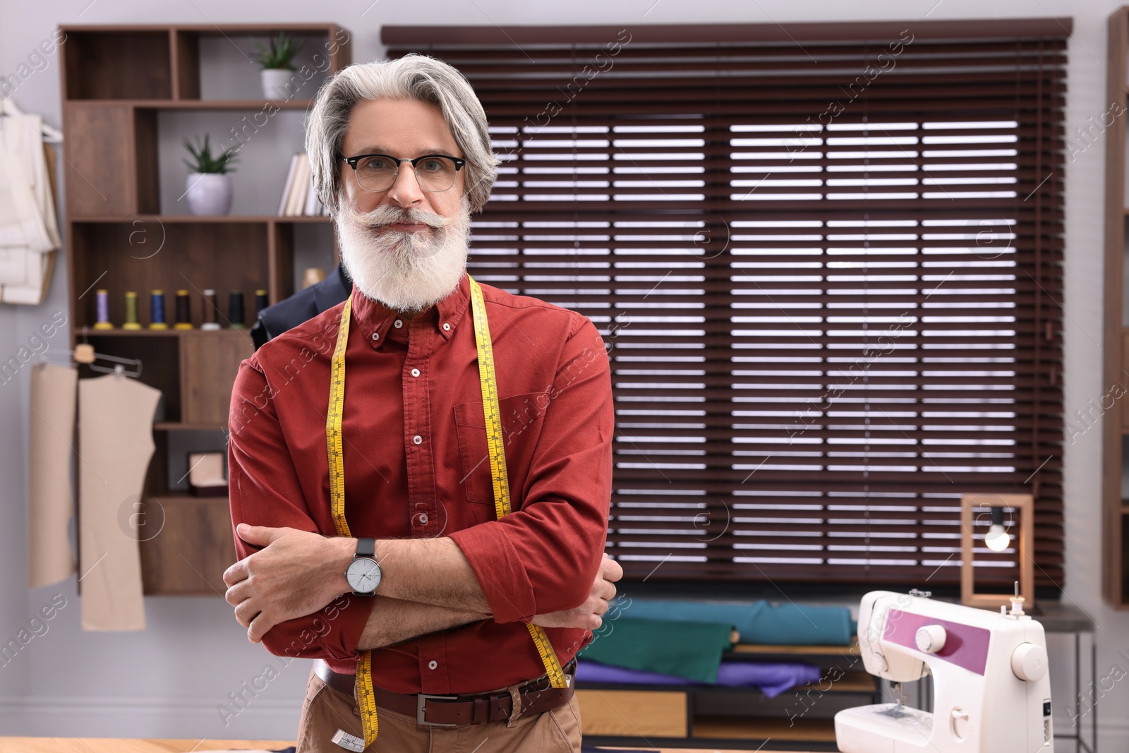 Photo of Professional tailor with measuring tape in workshop, space for text