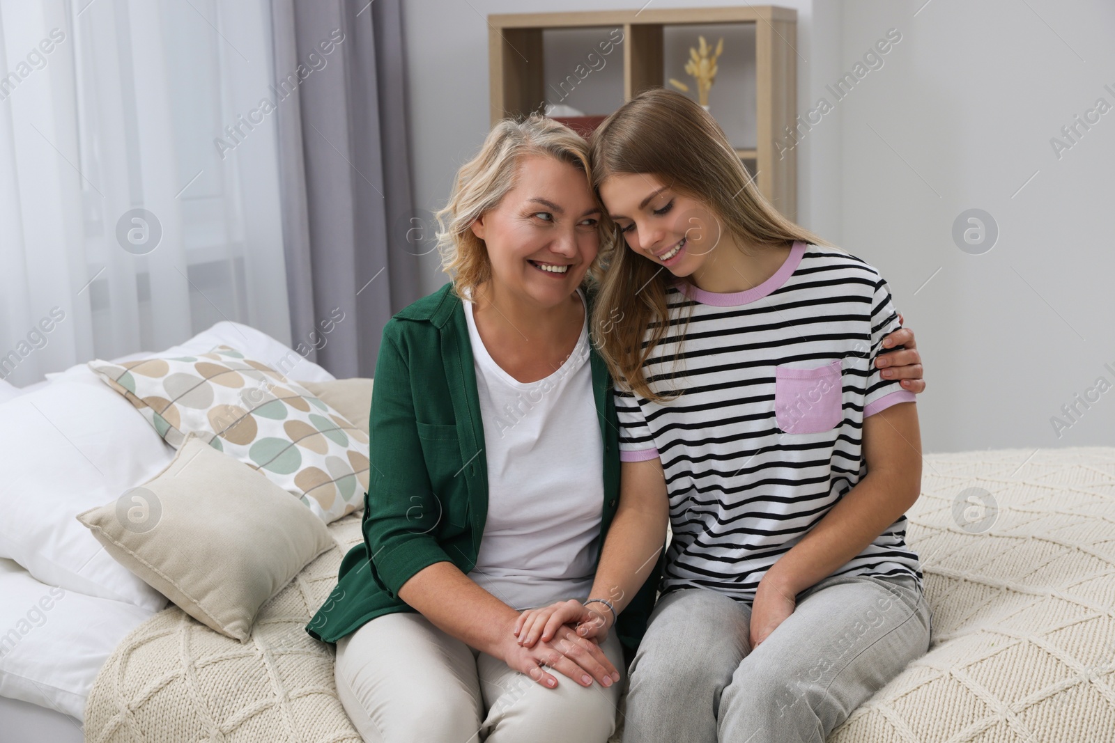 Photo of Young woman with her mom on bed at home. Happy Mother's Day