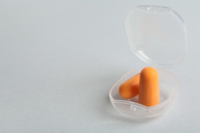 Photo of Pair of orange ear plugs in case on white background. Space for text