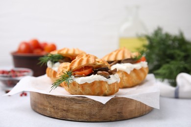 Photo of Delicious profiteroles with cream cheese, mushrooms, tomato and dill on white table, closeup