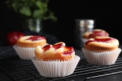 Delicious cupcakes with plums on black cooling tray, closeup