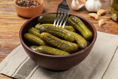 Photo of Eating tasty pickled cucumbers with fork at wooden table