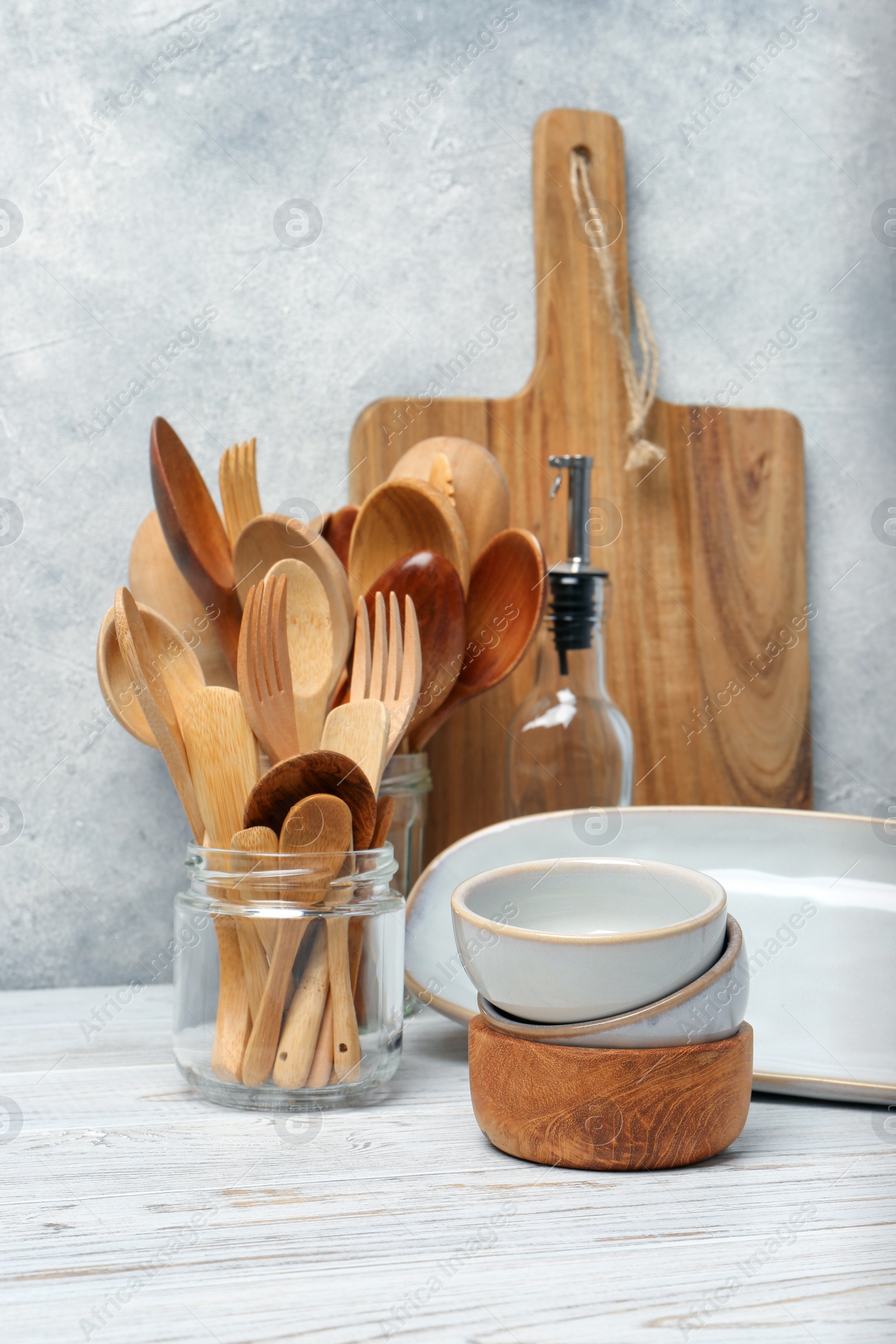 Photo of Different kitchenware and dishware on white wooden table against textured wall