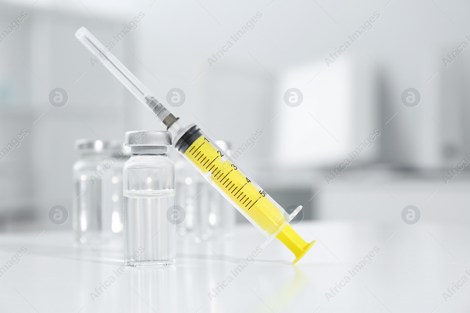 Photo of Syringe and vial of medicine on white table. Space for text