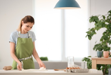 Photo of Woman preparing dough on table in kitchen