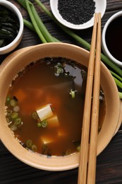 Bowl of delicious miso soup with tofu served on dark wooden table, flat lay