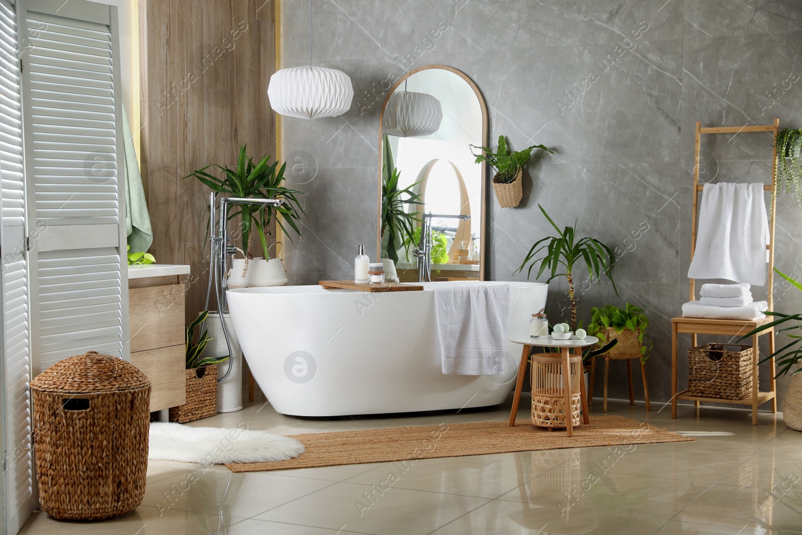 Photo of Modern white tub and beautiful green houseplants in bathroom. Interior design