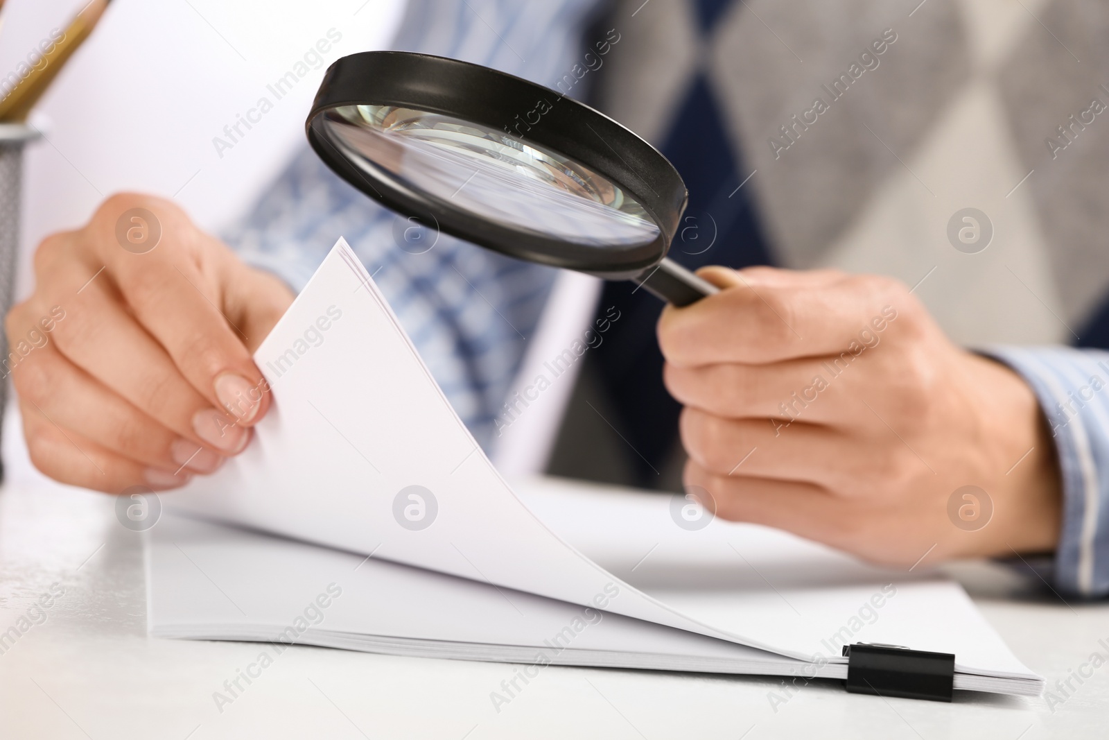 Photo of Woman using magnifying glass at table, closeup