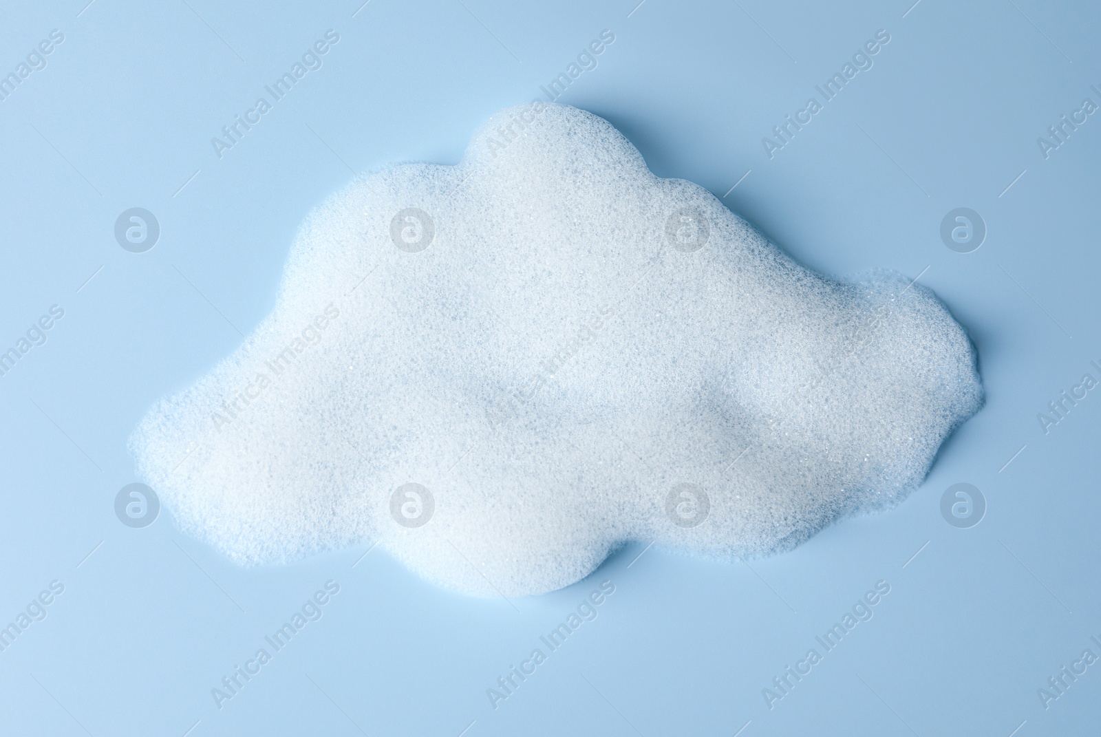 Photo of Foam sample in shape of cloud on light blue background, top view