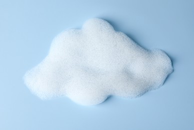 Photo of Foam sample in shape of cloud on light blue background, top view