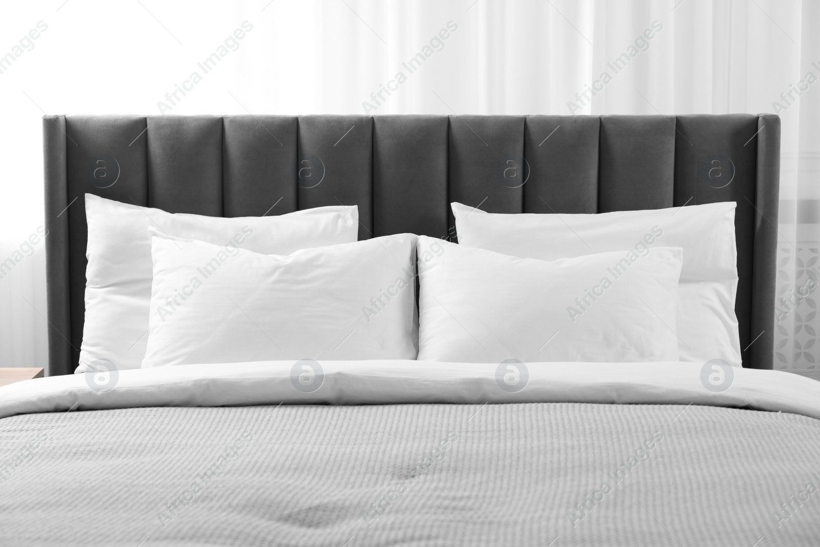 Photo of Soft white pillows and duvet on bed at home