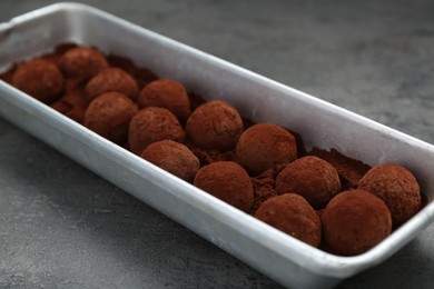 Delicious chocolate candies powdered with cocoa on grey table, closeup