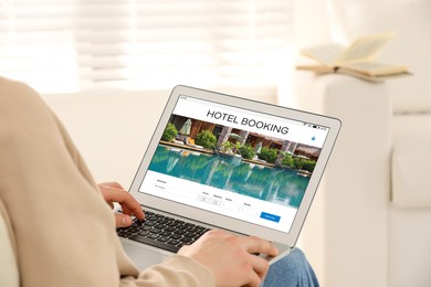 Image of Man using laptop to book hotel at home, closeup