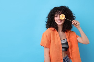 Photo of Beautiful woman with lollipop on light blue background, space for text