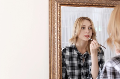 Young woman applying makeup near mirror in dressing room