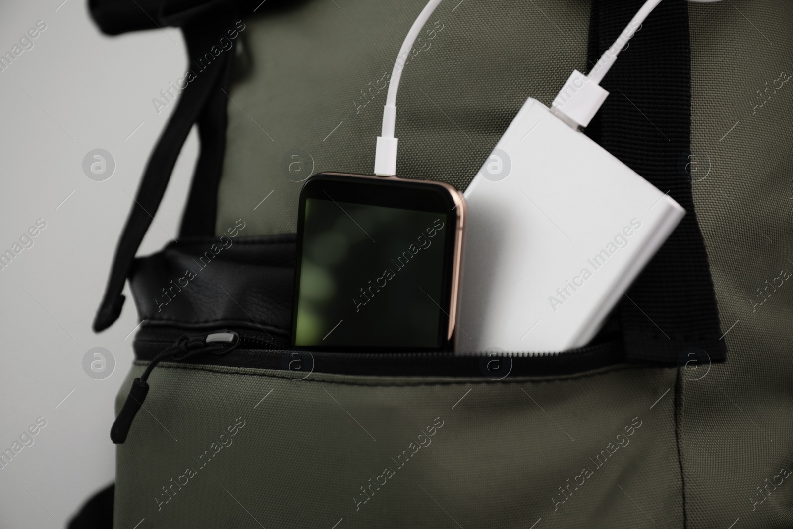 Photo of Smartphone charging with power bank in backpack, closeup