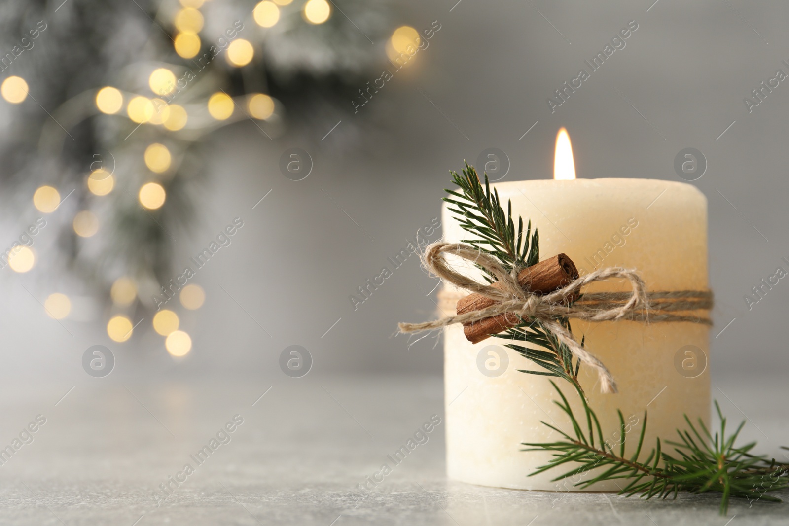 Photo of Burning candle with pinecone scent on light grey table, closeup. Space for text