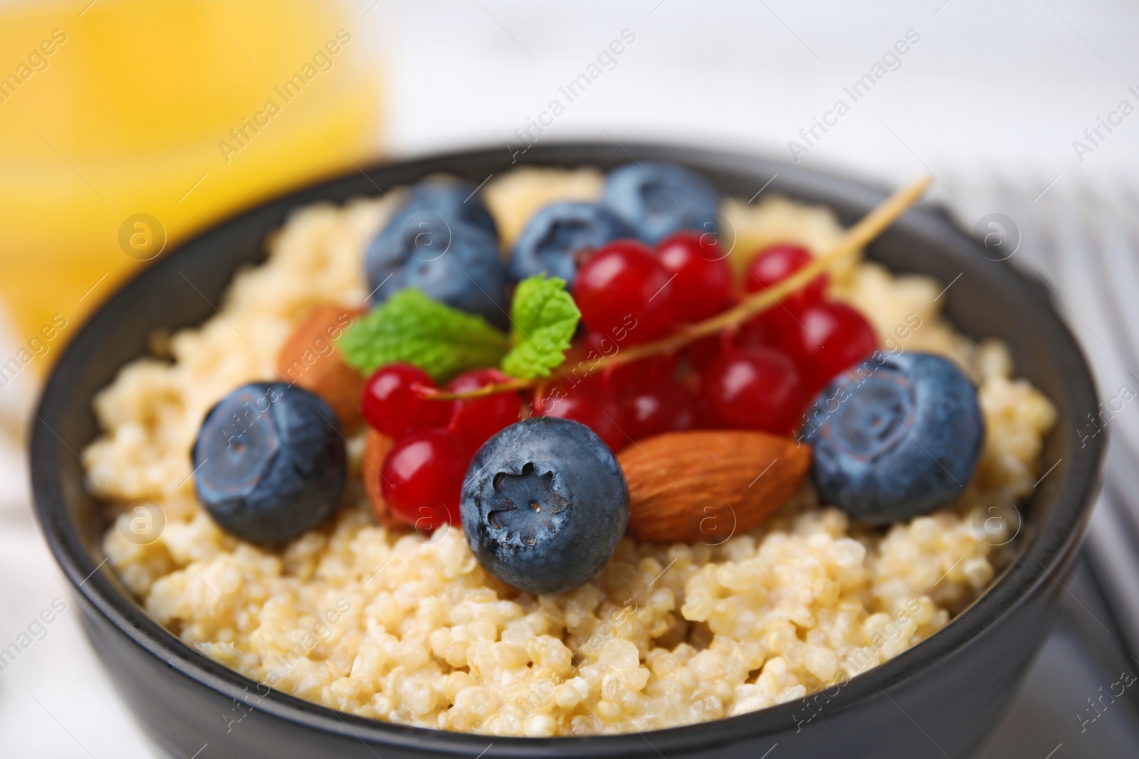 Photo of Bowl of delicious cooked quinoa with almonds, cranberries and blueberries, closeup