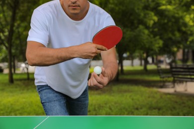 Photo of Man playing ping pong in park, closeup