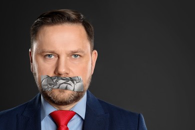 Image of Mature man with taped mouth on grey background. Speech censorship