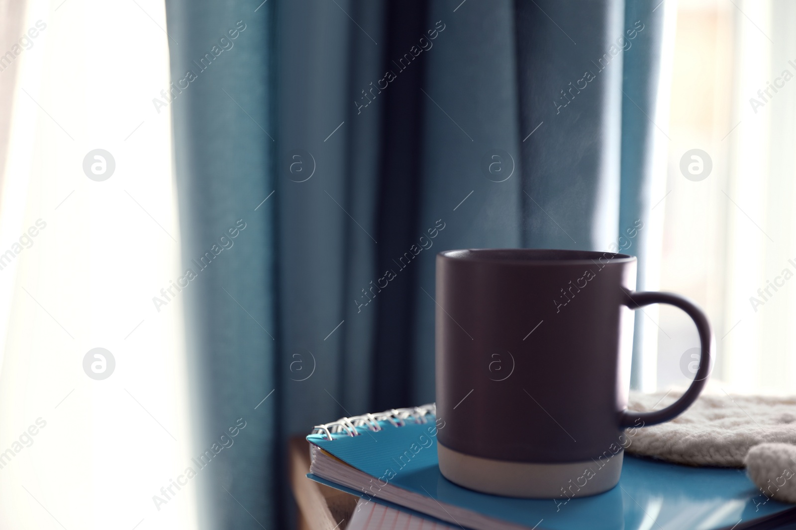 Photo of Delicious morning coffee and notebook near window indoors. Space for text