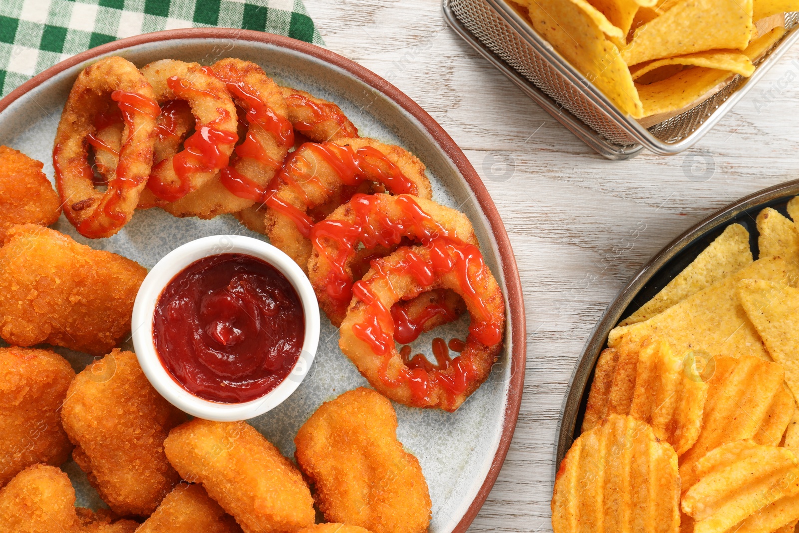 Photo of Different delicious fast food served with ketchup on white wooden table, flat lay