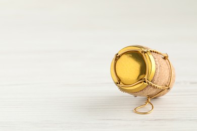 Cork of sparkling wine and muselet cap on white wooden table, closeup. Space for text