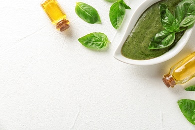 Photo of Sauce in gravy boat, basil oil and leaves on white table, top view with space for text