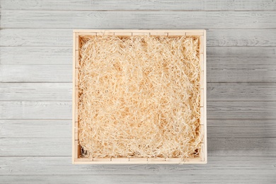 Photo of Wooden crate with filler on light background, top view