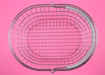 Empty metal shopping basket on pink background, top view