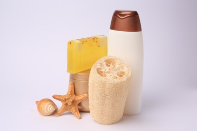 Photo of Natural loofah sponge, cosmetic products and seashells on white background