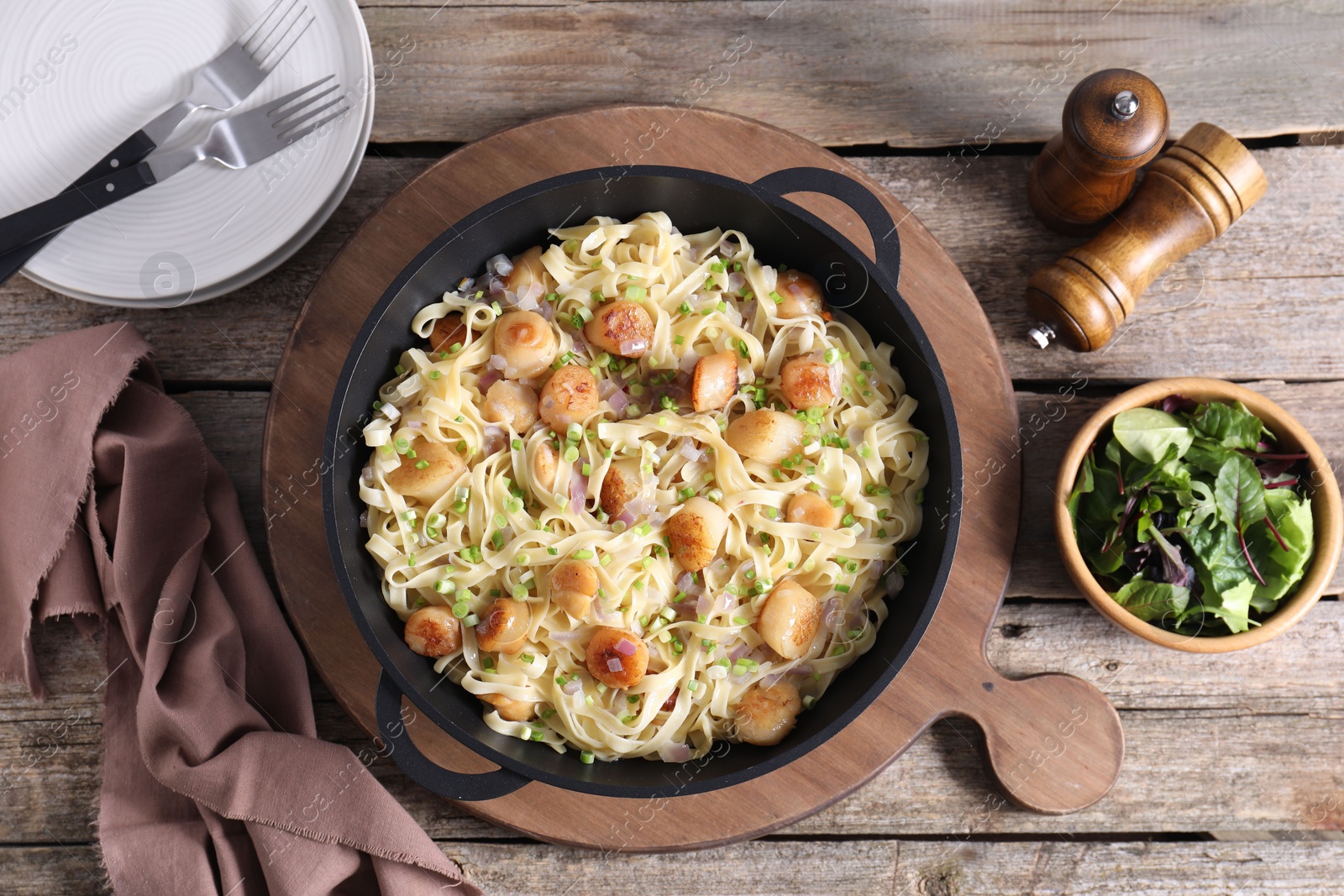 Photo of Delicious scallop pasta with onion served on wooden table, flat lay