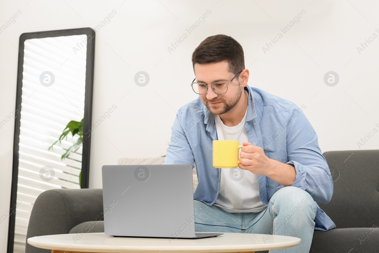 Photo of Man working with laptop at table in room