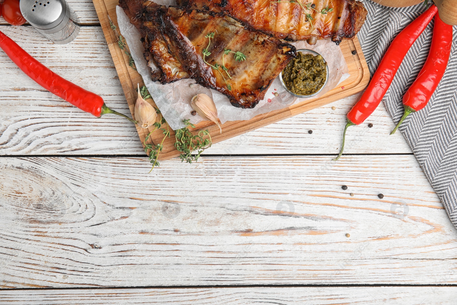 Photo of Tasty grilled ribs served on white wooden table, flat lay. Space for text