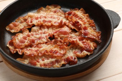Photo of Delicious bacon slices in frying pan on white wooden table, closeup