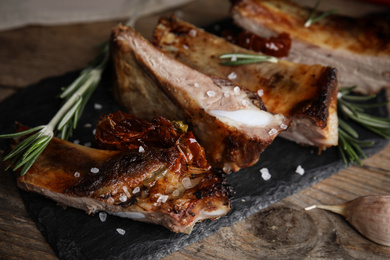 Tasty grilled ribs with rosemary on wooden table, closeup